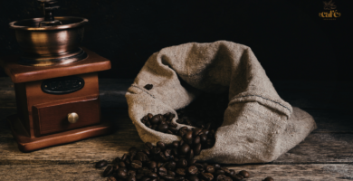 moedor de manivela ao lado de saco de tecido com grãos de café torrado, mostrando como moer café em casa sem moedor profissional