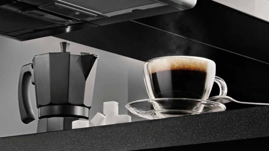 xícara de café ao lado de uma cafeteira italiana