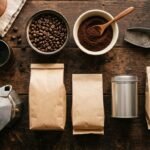 Pacotes de café, grãos torrados, café moído e cafeteira italiana sobre mesa de madeira