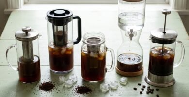 Cafeteiras e jarras de cold brew de vidro e plástico com café em infusão e cubos de gelo